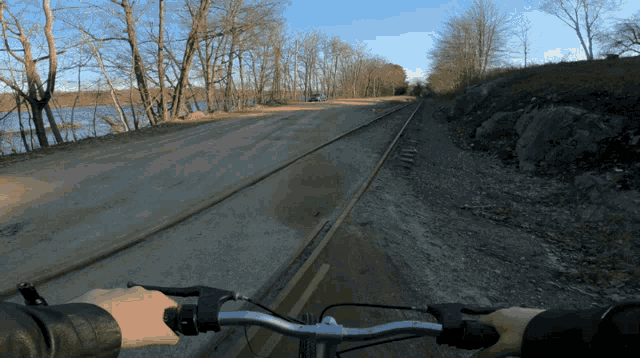 a person riding a bike on a dirt road next to train tracks