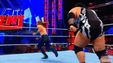 two wrestlers are fighting in a ring with a sign that says ' all ent ' on it