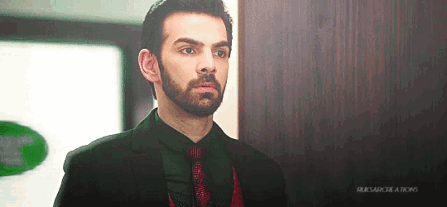 a man in a suit and tie is standing in front of a door that says rusarcreations