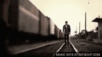 a man is walking along train tracks in front of a train .