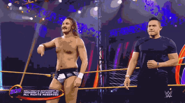 two men standing in a wrestling ring with a sign that says 205 on it