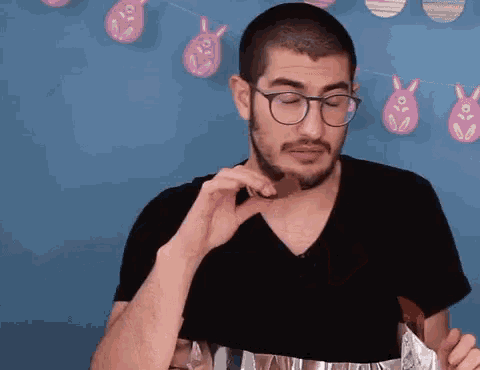 a man with glasses and a beard eating a chocolate bar