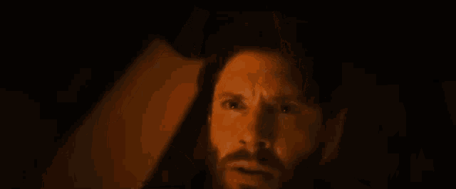 a man with a beard is sitting in a car with his eyes closed .