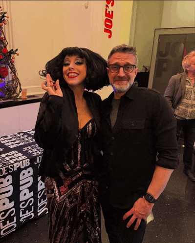a man and a woman are posing for a picture in front of a joe 's pub sign