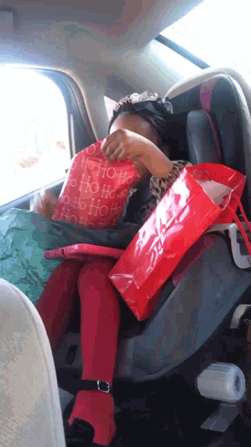 a child is sitting in a car seat with a red bag that says ho ho ho