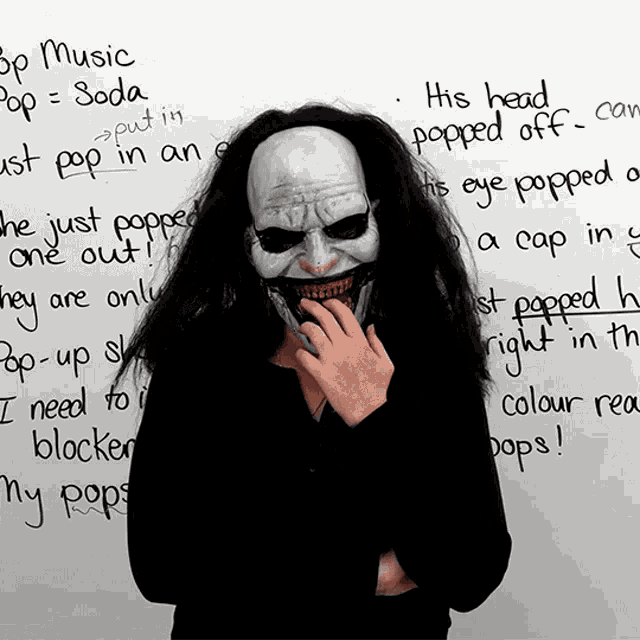 a person wearing a scary mask stands in front of a white board that says pop music pop - soda