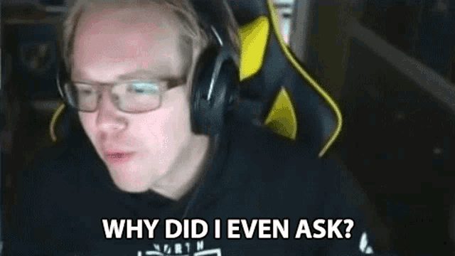 a man wearing headphones and glasses is sitting in front of a computer screen .
