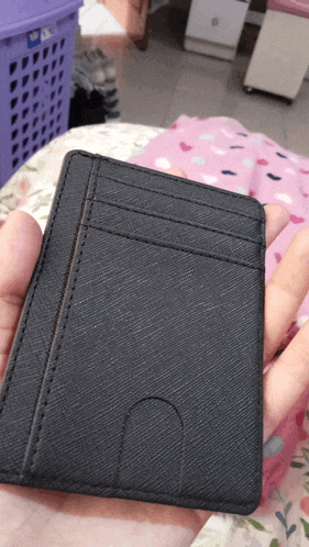 a person holding a black wallet with a hole in the middle