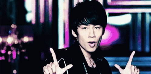 a young man is making a peace sign with his hands in front of a purple background .
