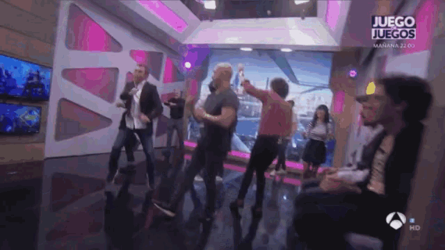 a group of people are dancing in front of a sign that says juegos
