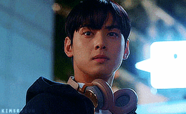 a young man wearing headphones is looking over his shoulder .