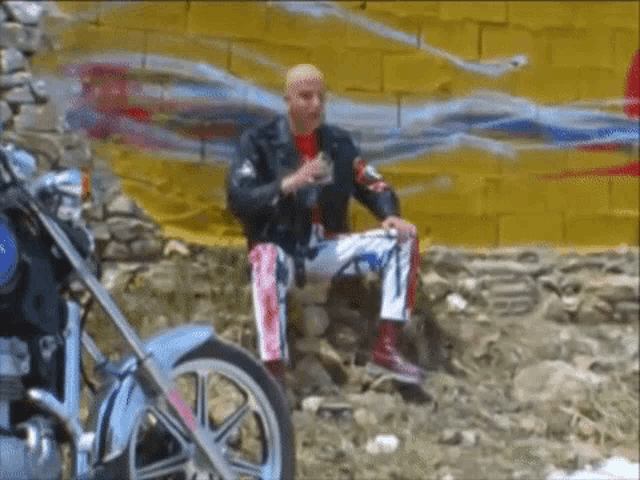 a man sitting on a rock next to a motorcycle with the word yamaha on the front