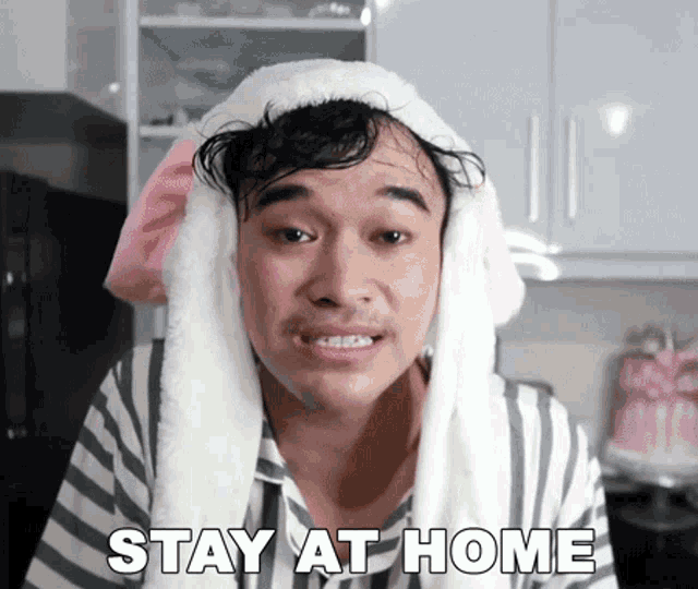 a man wearing bunny ears and a striped shirt says " stay at home "