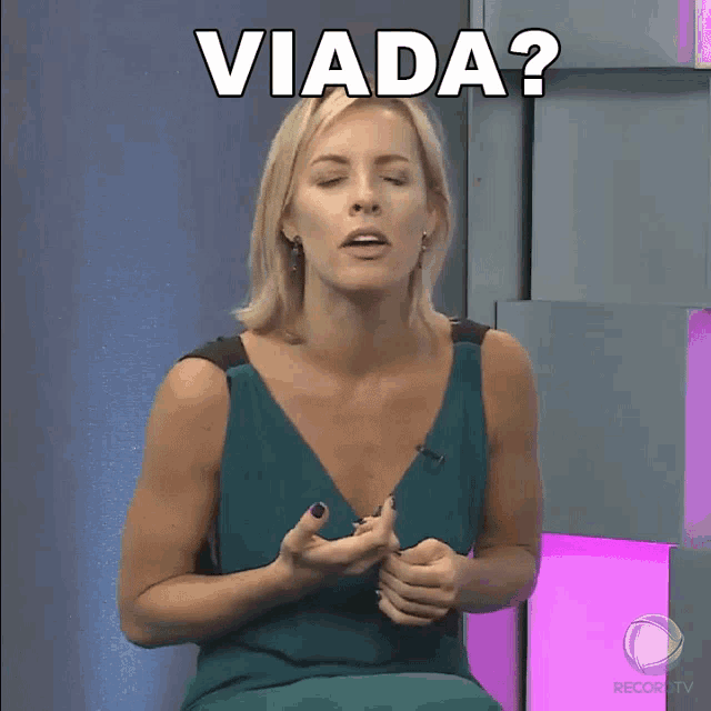 a woman in a green dress is sitting in front of a sign that says " viada "