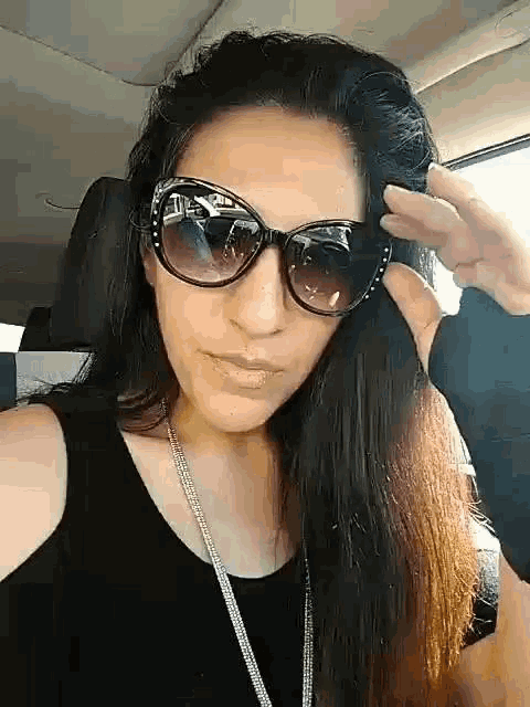 a woman wearing sunglasses is sitting in a car .
