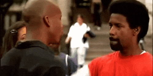 a man in a red shirt is talking to another man in a black shirt .