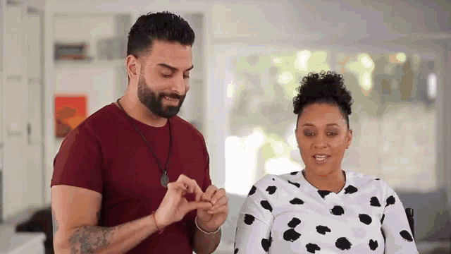 a man and a woman are making a heart shape with their hands