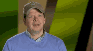 a man wearing a hat and a blue sweater is smiling