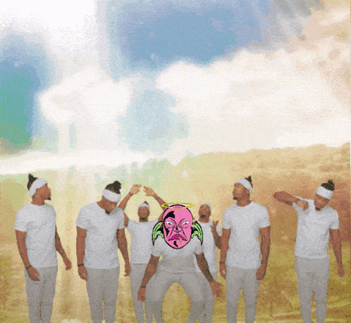 a group of men wearing white shirts and headbands are standing in a field with a man with a pink face and a halo