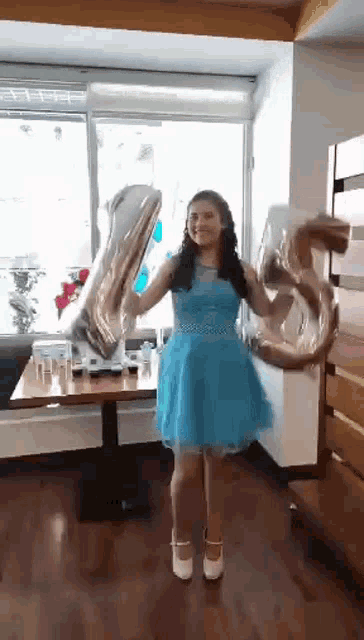 a girl in a blue dress is holding balloons that say 55