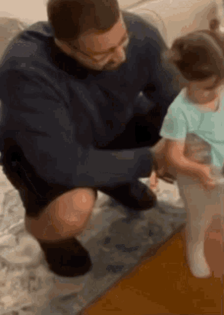 a man is kneeling down next to a little girl who is wearing white socks .