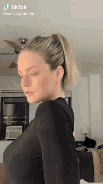 a woman is wearing a black shirt and a ponytail .