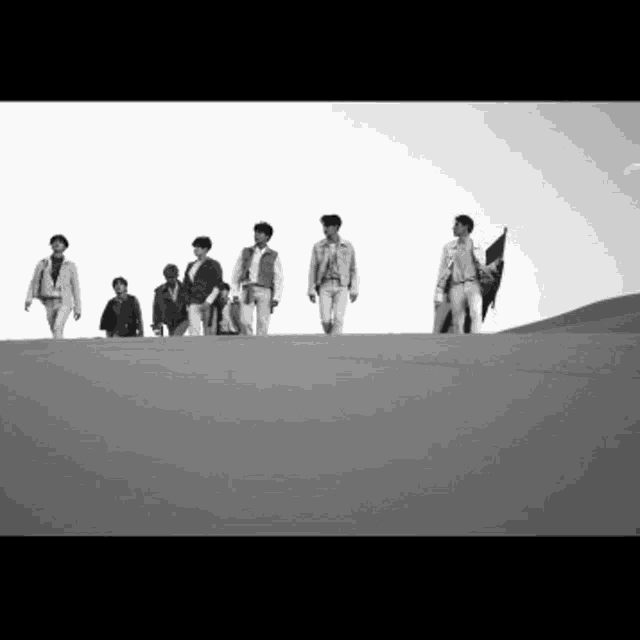 a black and white photo of a group of men walking in the desert .