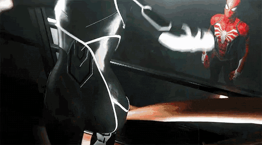a man in a spiderman costume is standing next to another man in a black suit .
