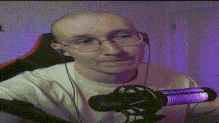 a bald man wearing glasses and earbuds is sitting in front of a microphone .
