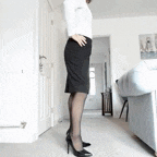 a woman in a black skirt and heels is standing in a living room .