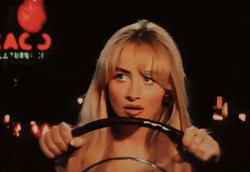 a woman driving a car with a texaco sign behind her