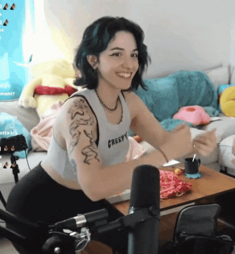 a woman wearing a creepy tank top is smiling in front of a microphone