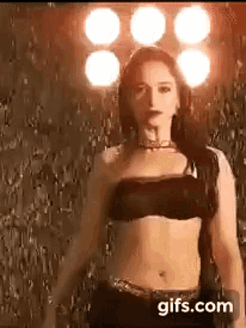 a woman in a black top is standing in front of a wall with lights behind her .
