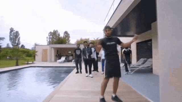 a group of young men are standing in front of a house with a swimming pool