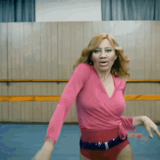 a woman in a pink top and red shorts is dancing in a dance studio