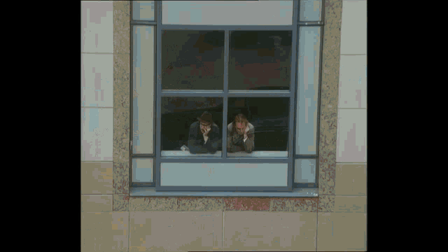 a man and a woman looking out of a window with their hands on their faces