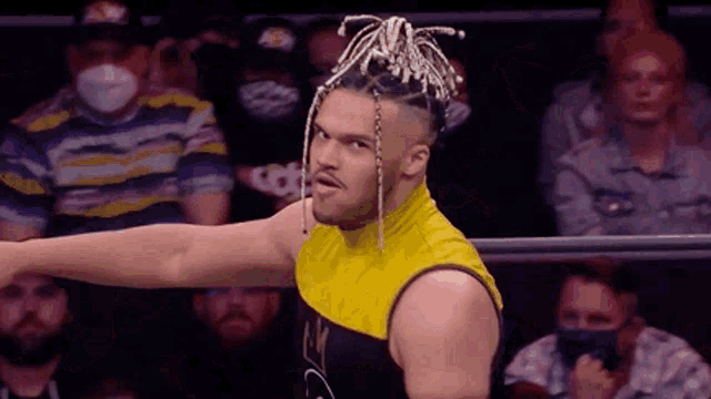 a wrestler with dreadlocks is standing in front of a crowd in a ring .