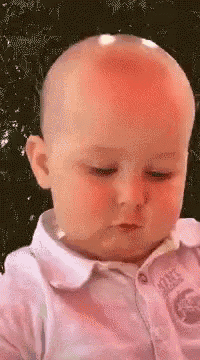 a baby with a bald head and a red spot on his forehead