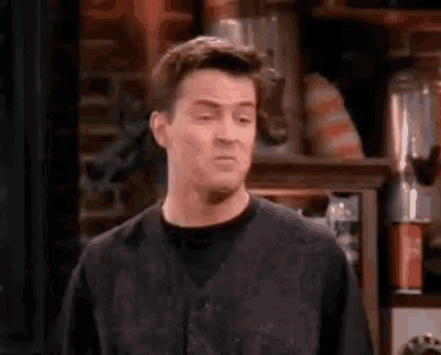 chandler bing from friends is making a funny face while standing in front of a blender .
