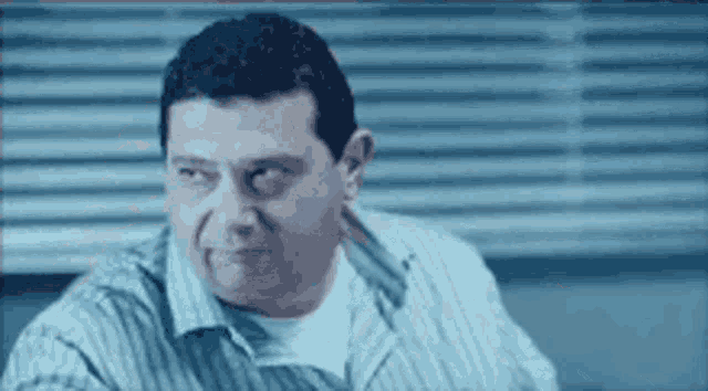 a man in a striped shirt is sitting in front of a window .
