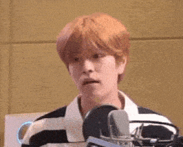 a man with red hair is sitting in front of a microphone making a funny face .