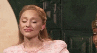 a woman in a pink dress is smiling and making a face .