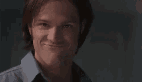 a close up of a man making a funny face while wearing a blue shirt .