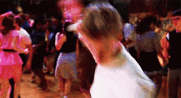 a man in a white shirt is dancing in a crowded room