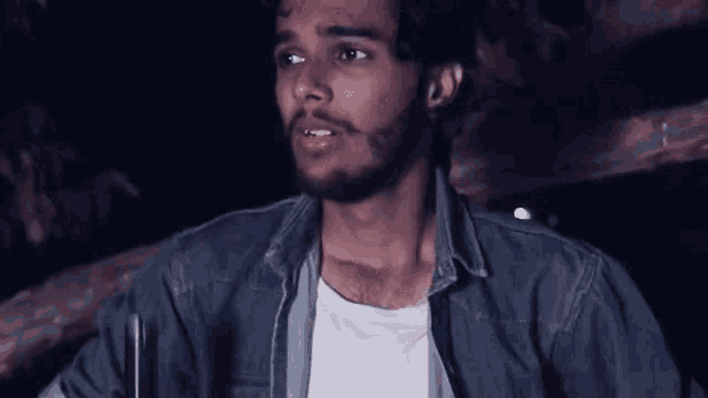 a man with a beard is wearing a blue shirt and a white shirt and looking at the camera .