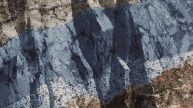 a close up of a rocky cliff with a blue stripe on the bottom