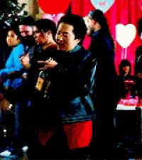 a group of people are dancing in front of a red curtain and balloons