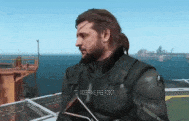 a man with a beard is standing on a roof overlooking the ocean holding a gun .