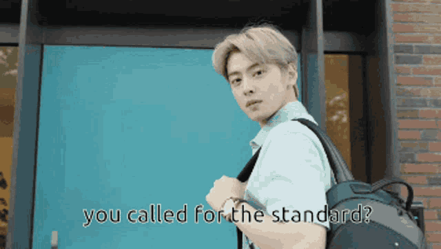 a man with a backpack is standing in front of a blue door with the words " you called for the standard " written below him