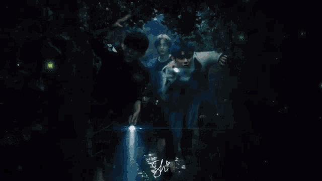 a group of people are standing in a dark forest holding flashlights